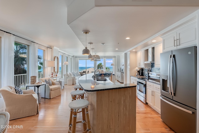 kitchen featuring appliances with stainless steel finishes, light hardwood / wood-style floors, white cabinetry, sink, and wall chimney range hood