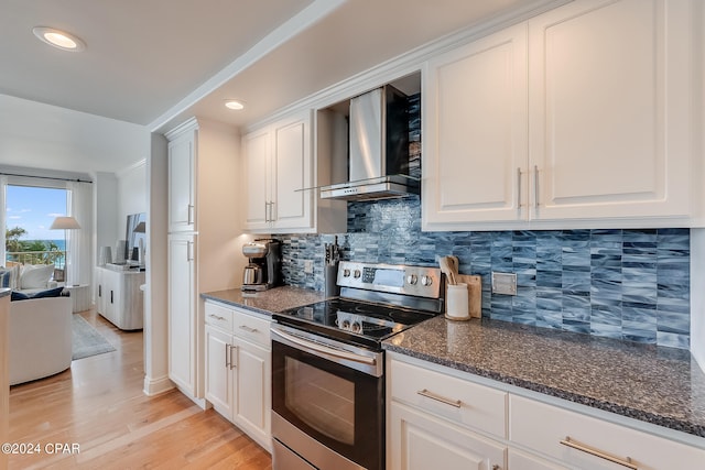 kitchen with light hardwood / wood-style flooring, decorative backsplash, white cabinetry, stainless steel electric range oven, and wall chimney range hood