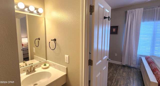 bathroom featuring a textured wall, a sink, and wood finished floors