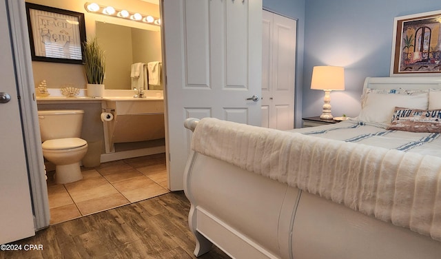 bedroom with dark wood finished floors, ensuite bath, and a sink