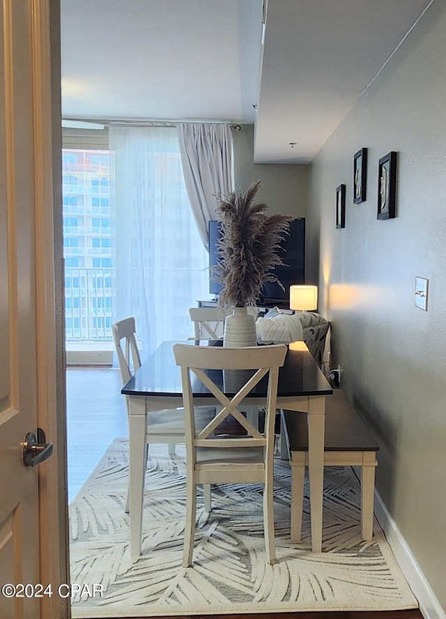 dining space featuring floor to ceiling windows, wood finished floors, and baseboards