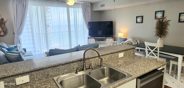 kitchen with visible vents, dishwasher, open floor plan, stone counters, and a sink