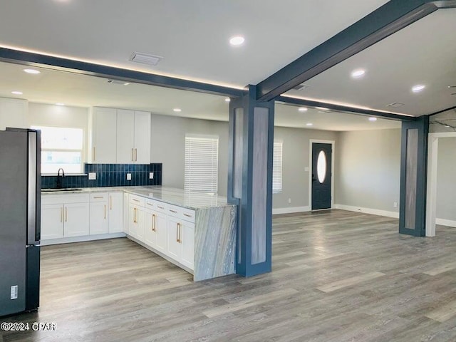 kitchen with tasteful backsplash, stainless steel fridge, white cabinets, and light hardwood / wood-style flooring