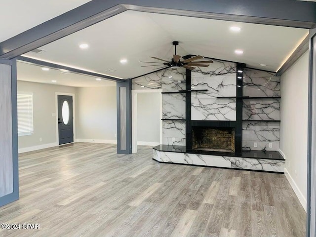 unfurnished living room with a premium fireplace, lofted ceiling, ceiling fan, and light hardwood / wood-style flooring