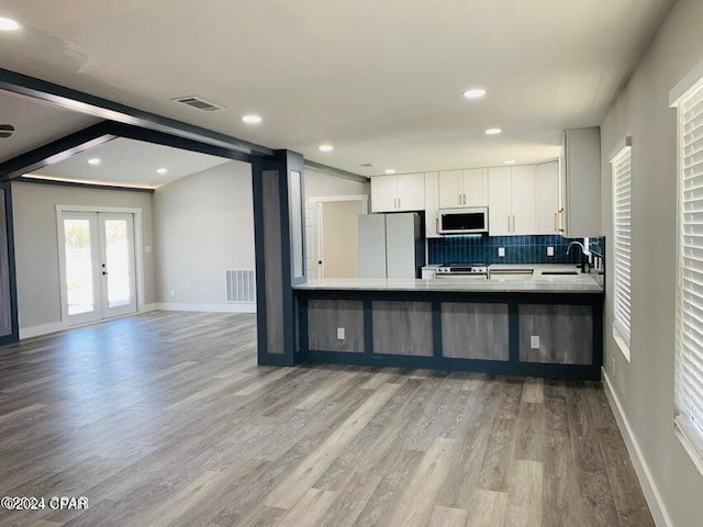 kitchen with sink, white cabinetry, tasteful backsplash, stainless steel fridge, and kitchen peninsula