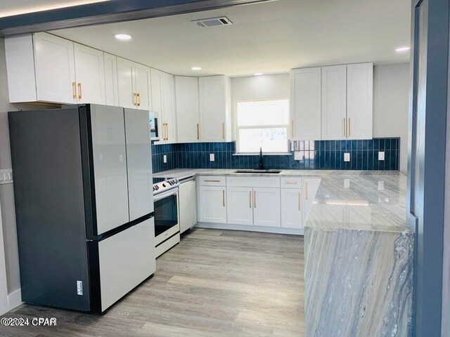 kitchen featuring tasteful backsplash, vaulted ceiling with beams, light hardwood / wood-style flooring, white cabinets, and white fridge