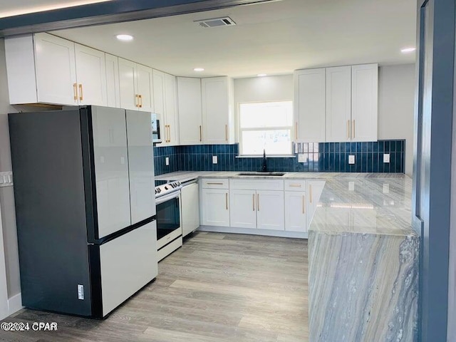 kitchen featuring light hardwood / wood-style floors, electric range oven, white cabinetry, and white fridge