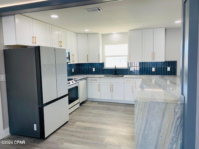 kitchen featuring fridge, range with electric stovetop, light stone counters, and white cabinets