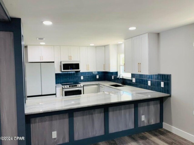 kitchen featuring white cabinets, sink, tasteful backsplash, light hardwood / wood-style floors, and kitchen peninsula