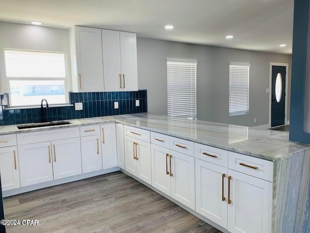 kitchen featuring sink, light hardwood / wood-style floors, kitchen peninsula, and white cabinets