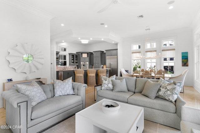 living room featuring sink, ceiling fan with notable chandelier, and ornamental molding