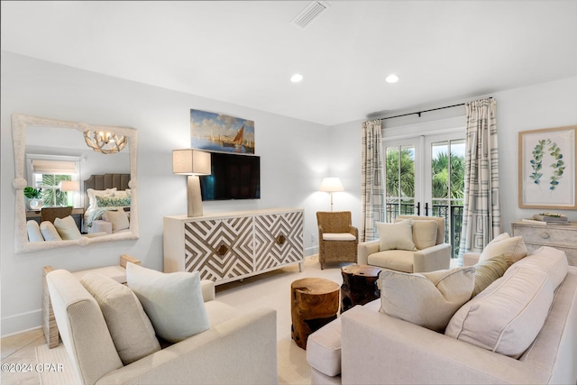 living room featuring plenty of natural light, a chandelier, and french doors