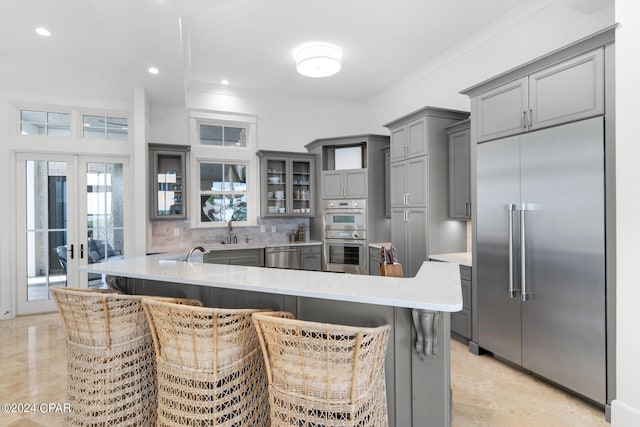 kitchen with kitchen peninsula, appliances with stainless steel finishes, a breakfast bar area, and gray cabinetry