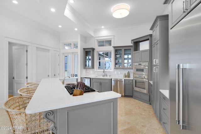 kitchen featuring appliances with stainless steel finishes, a center island, gray cabinets, and a breakfast bar area