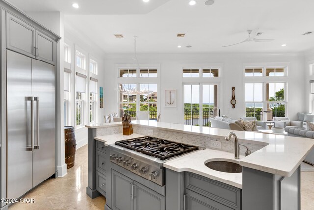 kitchen with light stone countertops, stainless steel appliances, ceiling fan, sink, and gray cabinets