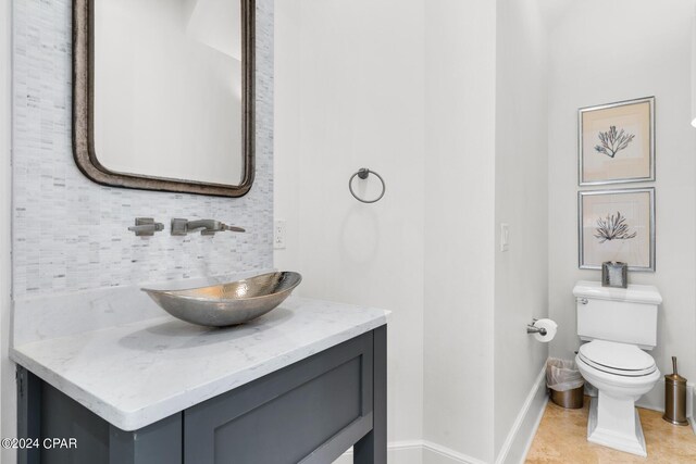 bathroom featuring tile patterned flooring, vanity, tasteful backsplash, and toilet