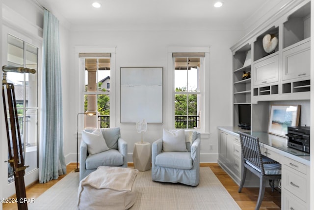 home office with built in desk, light hardwood / wood-style floors, and ornamental molding