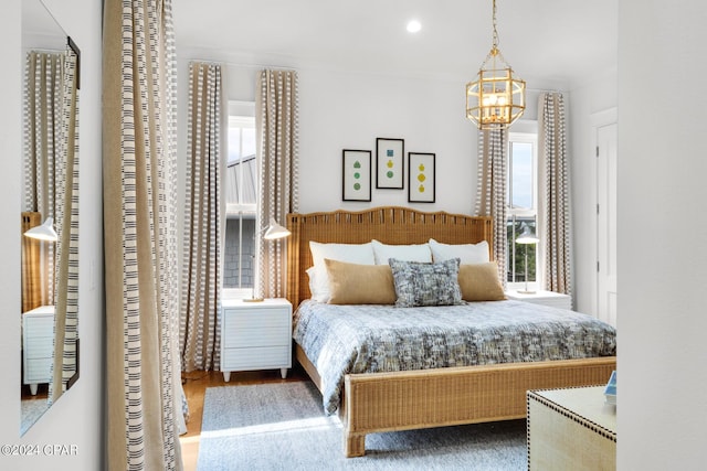 bedroom with multiple windows, hardwood / wood-style floors, and a notable chandelier