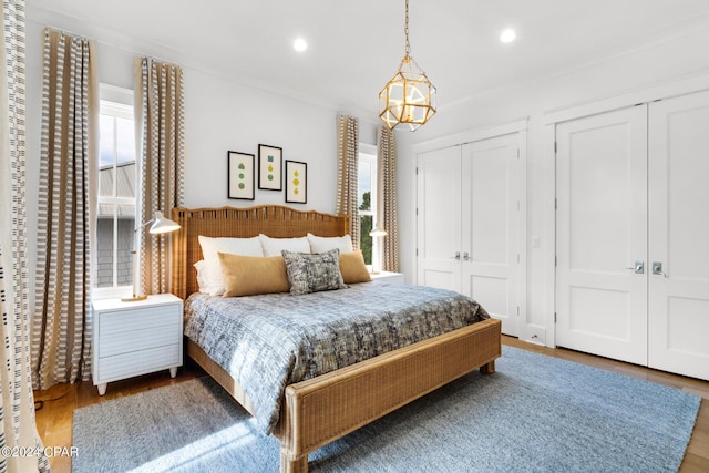 bedroom with hardwood / wood-style flooring, a chandelier, two closets, and multiple windows