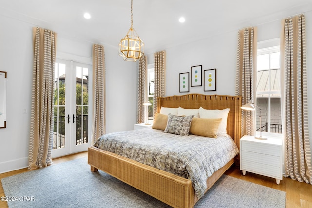 bedroom featuring access to exterior, hardwood / wood-style floors, a chandelier, and french doors