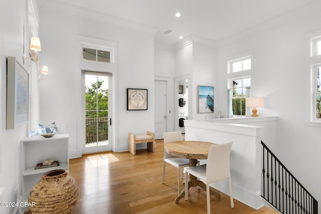 interior space with ornamental molding, light wood-type flooring, plenty of natural light, and stacked washer and clothes dryer