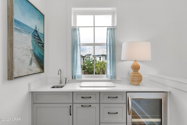 bar with wine cooler, sink, and gray cabinets