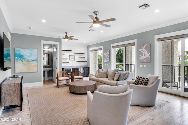 living room featuring ceiling fan, sink, light hardwood / wood-style floors, and ornamental molding