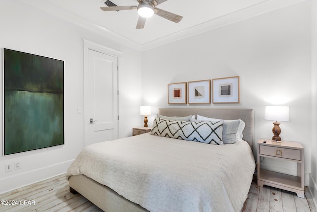 bedroom featuring light hardwood / wood-style flooring, ceiling fan, and crown molding