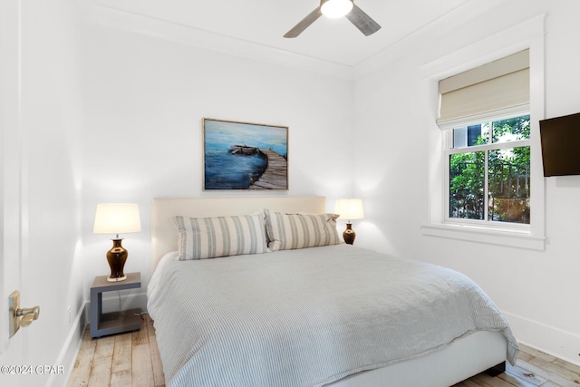 bedroom featuring ceiling fan, ornamental molding, and light hardwood / wood-style flooring