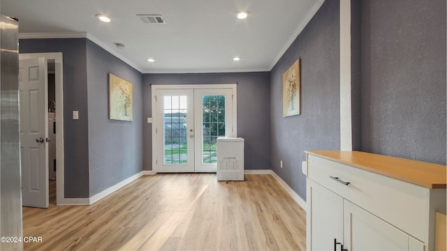 entryway with light hardwood / wood-style floors, crown molding, and french doors