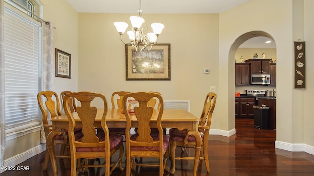 dining area with dark wood-type flooring and an inviting chandelier