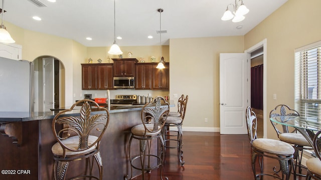 kitchen with dark stone countertops, stove, pendant lighting, and dark hardwood / wood-style flooring