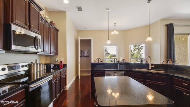 kitchen with sink, hanging light fixtures, an island with sink, dark hardwood / wood-style floors, and stainless steel appliances