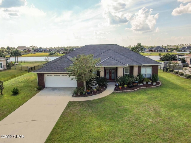 ranch-style house with a front yard, a garage, and a water view