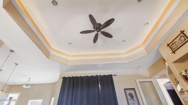 interior details featuring ceiling fan, a raised ceiling, and ornamental molding