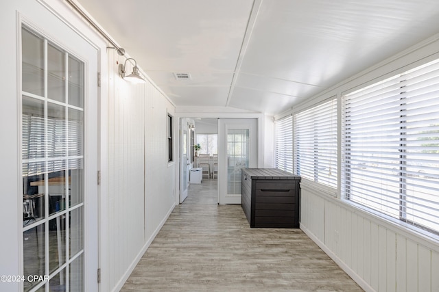 corridor with light wood-type flooring and vaulted ceiling