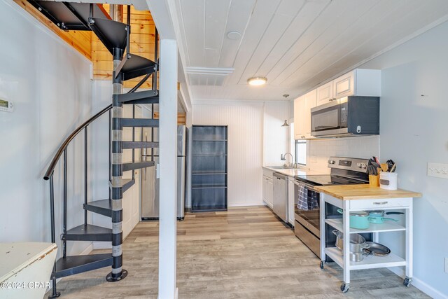 kitchen with butcher block counters, light hardwood / wood-style floors, white cabinets, backsplash, and stainless steel appliances