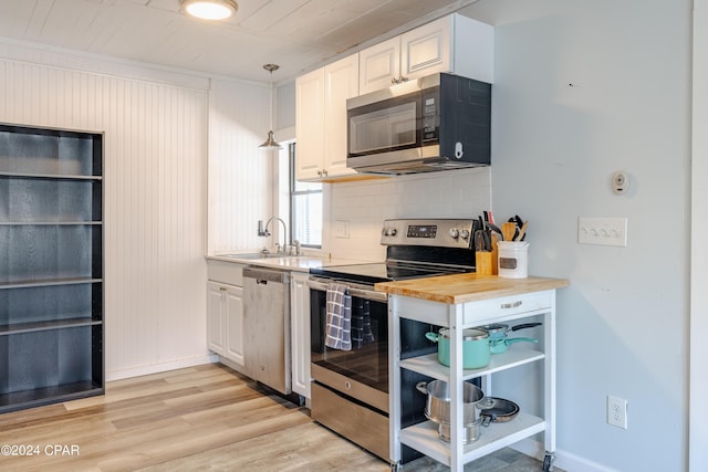 kitchen featuring appliances with stainless steel finishes, white cabinetry, butcher block counters, sink, and hanging light fixtures