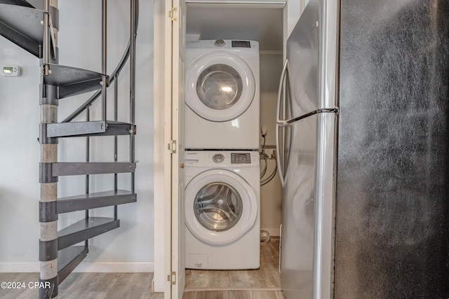 laundry area featuring light hardwood / wood-style floors and stacked washer / dryer