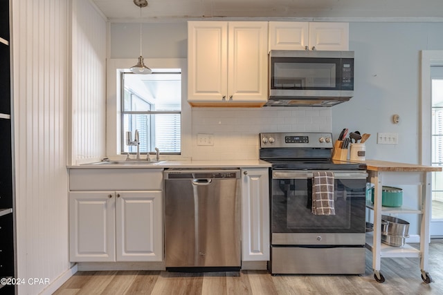 kitchen featuring pendant lighting, white cabinetry, stainless steel appliances, decorative backsplash, and sink