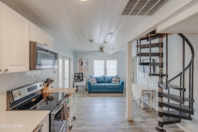 kitchen featuring appliances with stainless steel finishes, white cabinetry, tasteful backsplash, light hardwood / wood-style floors, and ceiling fan