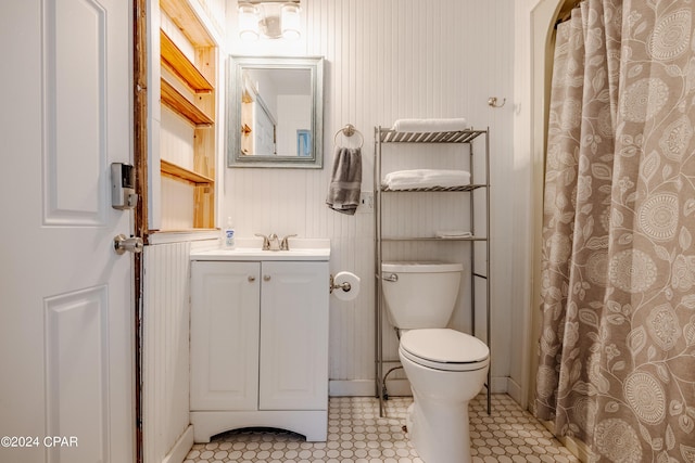 bathroom with toilet, vanity, walk in shower, and tile patterned flooring