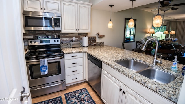 kitchen featuring appliances with stainless steel finishes, kitchen peninsula, white cabinets, and backsplash