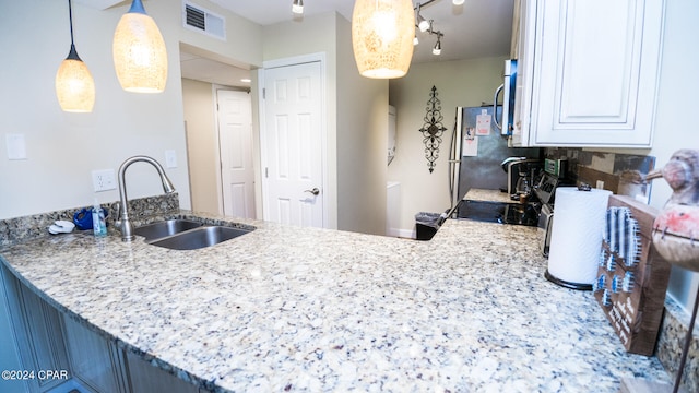 kitchen featuring white cabinets, light stone countertops, stainless steel range oven, pendant lighting, and sink