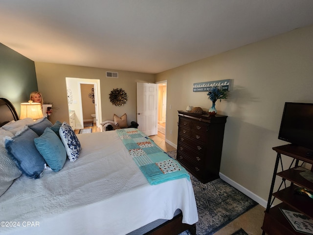 bedroom featuring ensuite bathroom and light tile patterned floors