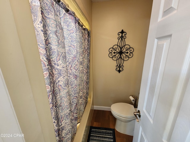 bathroom featuring toilet, curtained shower, and wood-type flooring