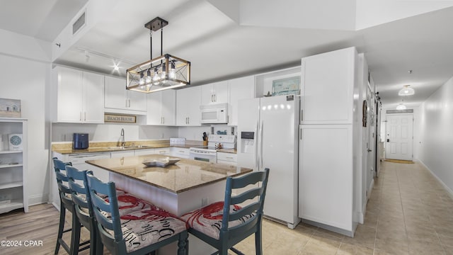 kitchen featuring white cabinetry, sink, white appliances, and a kitchen island