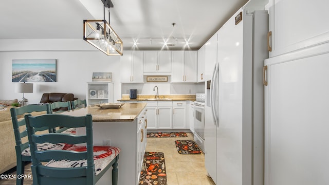 kitchen with light tile patterned floors, light stone countertops, white cabinetry, rail lighting, and decorative light fixtures