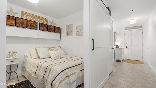 bedroom featuring a barn door and light tile patterned floors