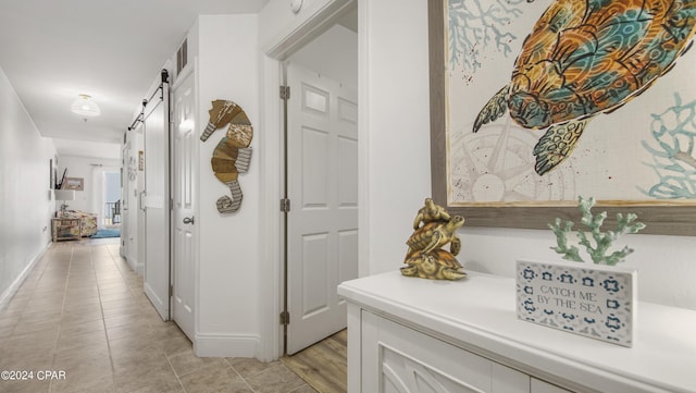 hallway with light tile patterned floors and a barn door